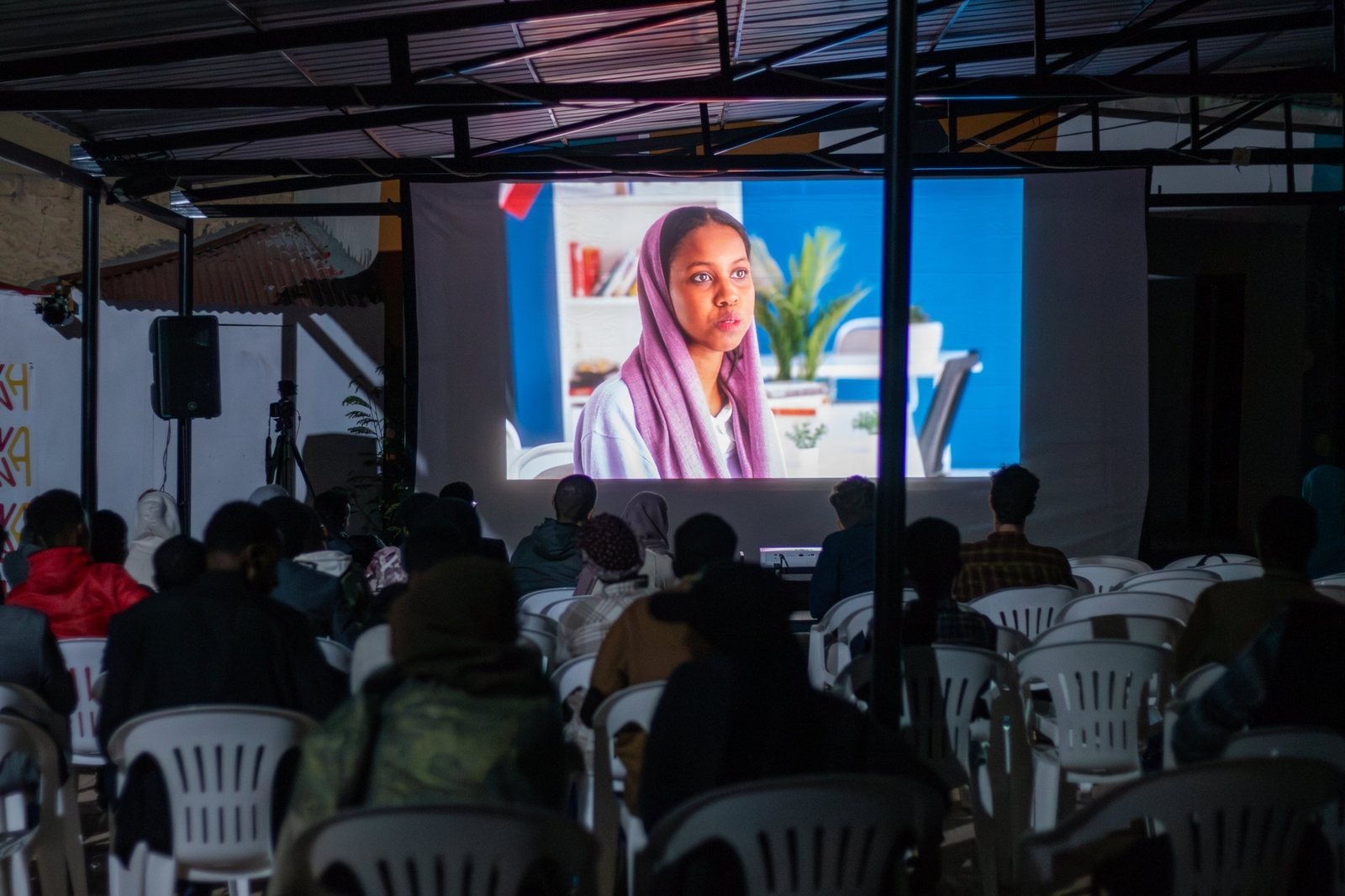 The audience watches a film on the big screen under the courtyard roof