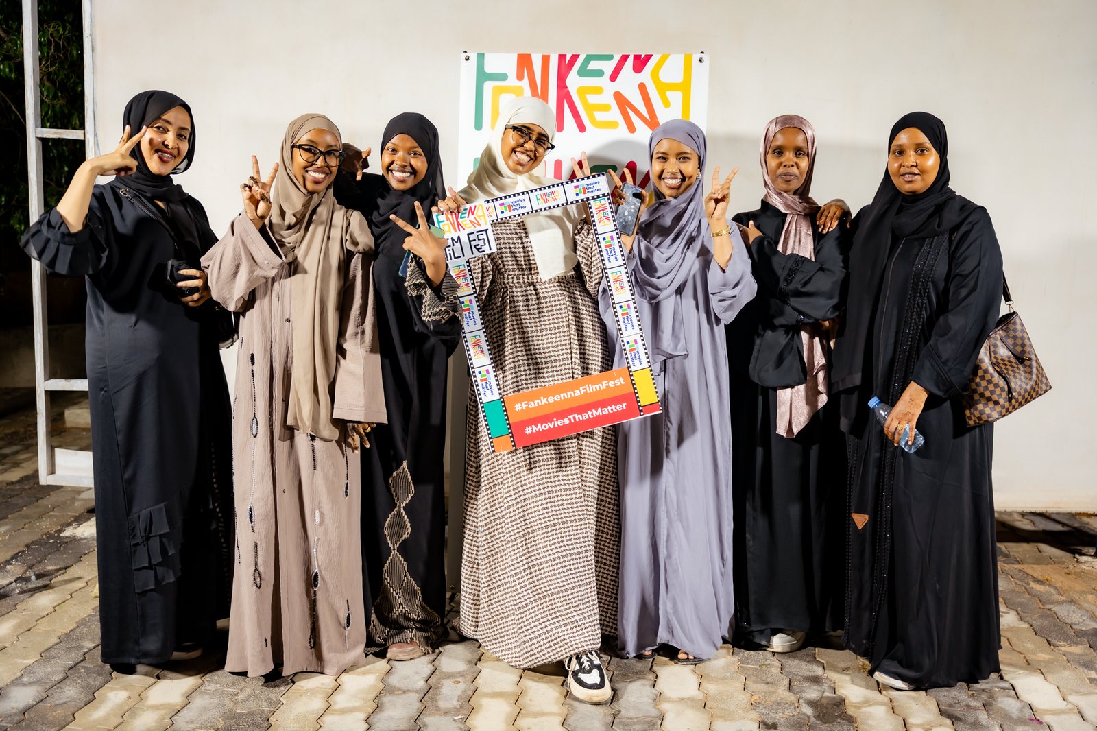 Seven women pose with the festival photo frame in front of the Fankeenna sign