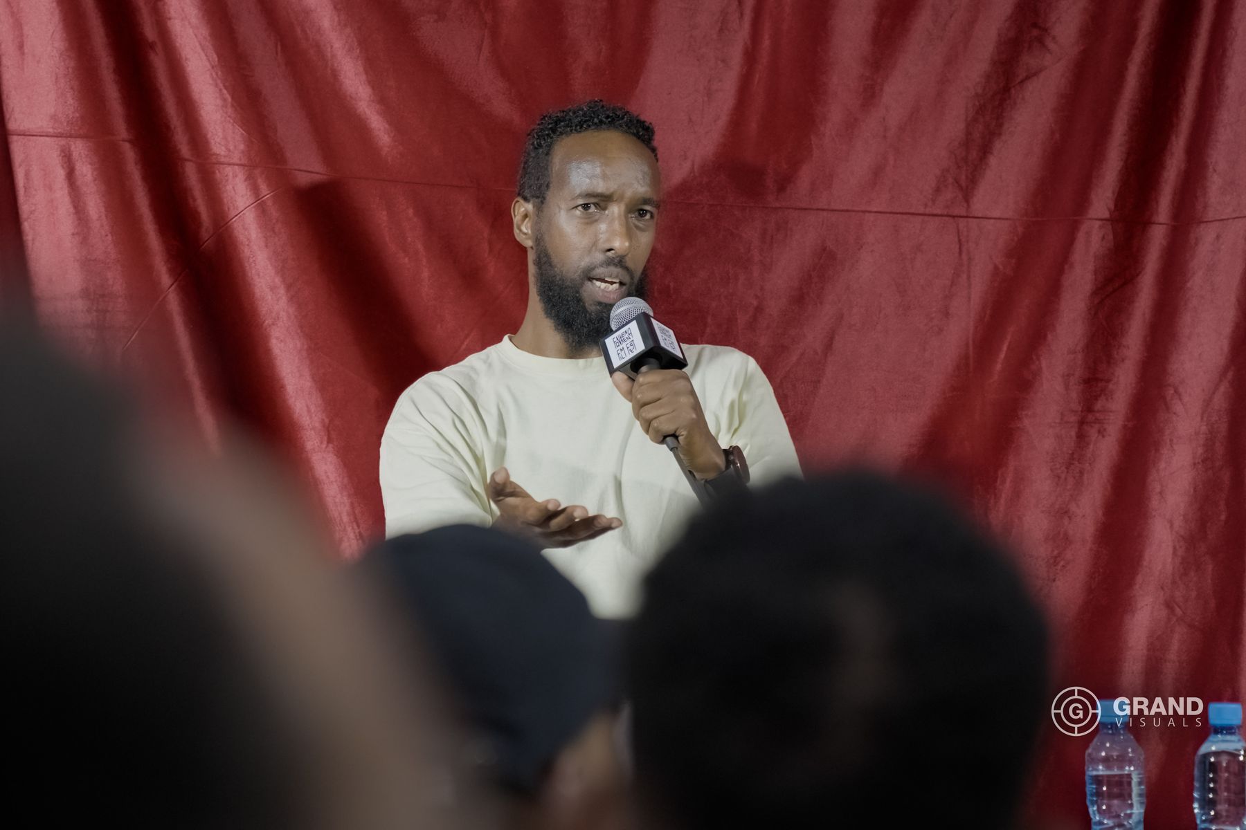 A guest speaks on the stage in front of the red curtain