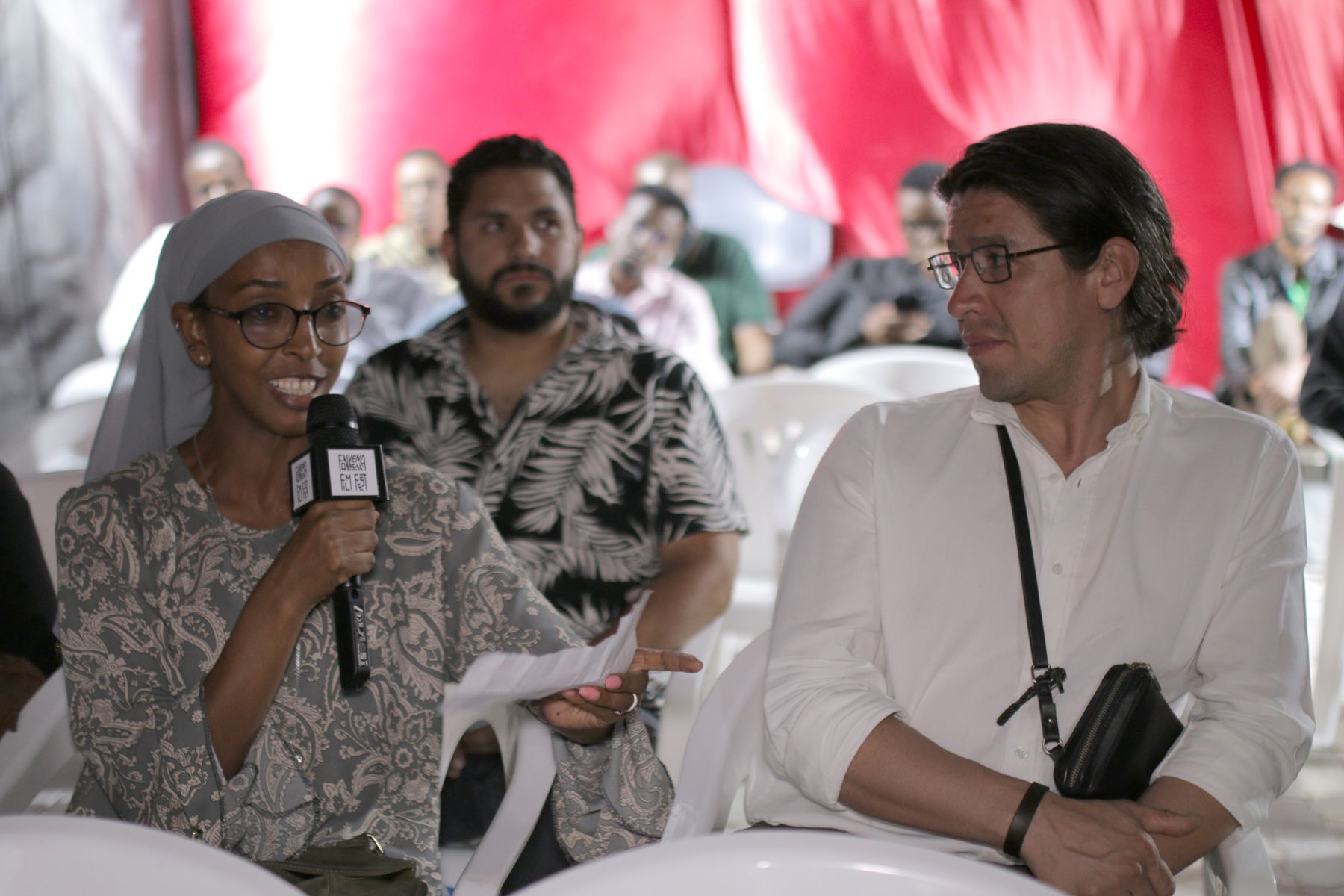 A woman in the audience speaks into the microphone while others listen
